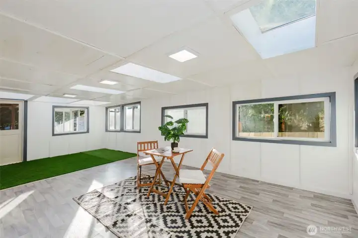 Light-filled enclosed sunroom with skylights, providing year-round usable space for relaxing or entertaining.