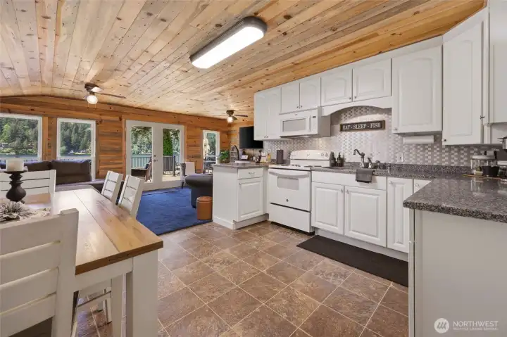A wide look at the kitchen flowing into the main living space, table to the left.  STAGING ITEMS can be purchased for $8k- talk to friendly Listing Agent before including in contract please.