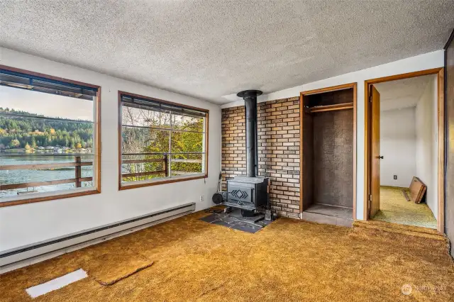 Living room, wood stove, and access to primary bedroom.