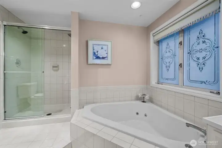 Primary jetted tub and separate shower with custom tile surround.