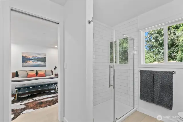 Spacious primary suite with tiled shower and frameless glass
