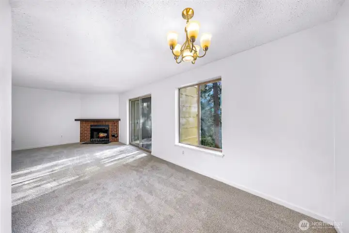 A large dining and living area with a wood-burning fireplace. The sliding glass door opens to a southeast-facing balcony with a territorial view.