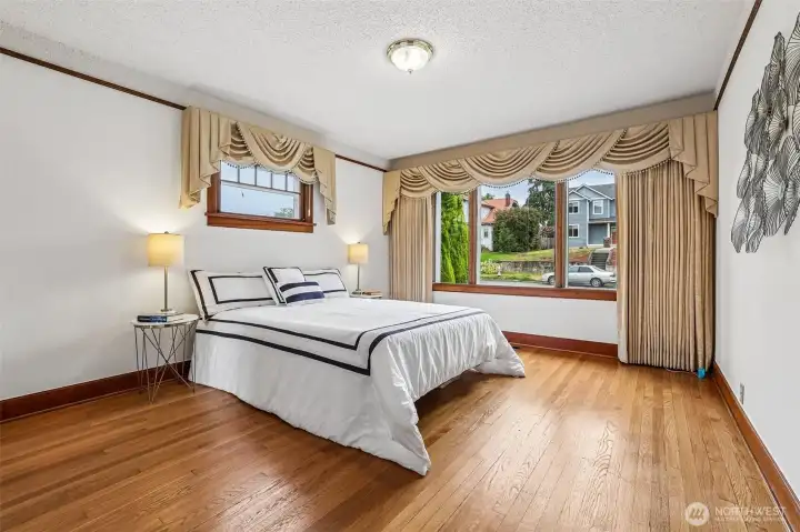 Main floor primary bedroom with hardwood floors, wood wrapped windows & a walk-in closet.