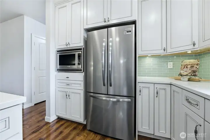 Modern kitchen space complete with new refrigerator and dishwasher.