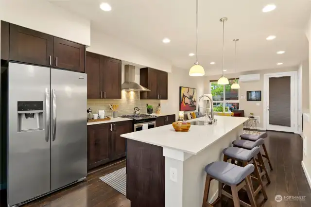 Open style living with hardwood floors, Ductless Mini-Split for A/C, kitchen island with seating, quartz countertops, stainless appliances plus an abundance of cabinets.