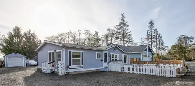 The side door enters into the kitchen, and behind the home is the shed, studio ADU, and an additional garage, along with RV hookups and parking.