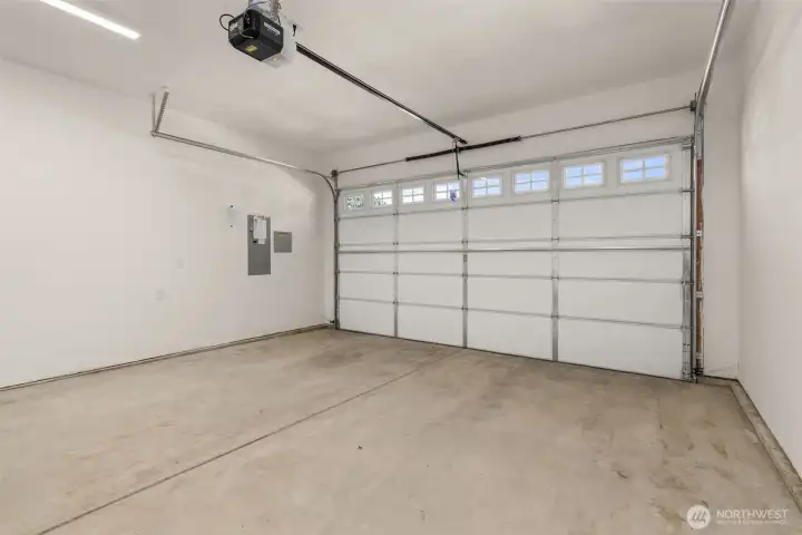 Two car garage with opener, walls are fully primed for a finished look.