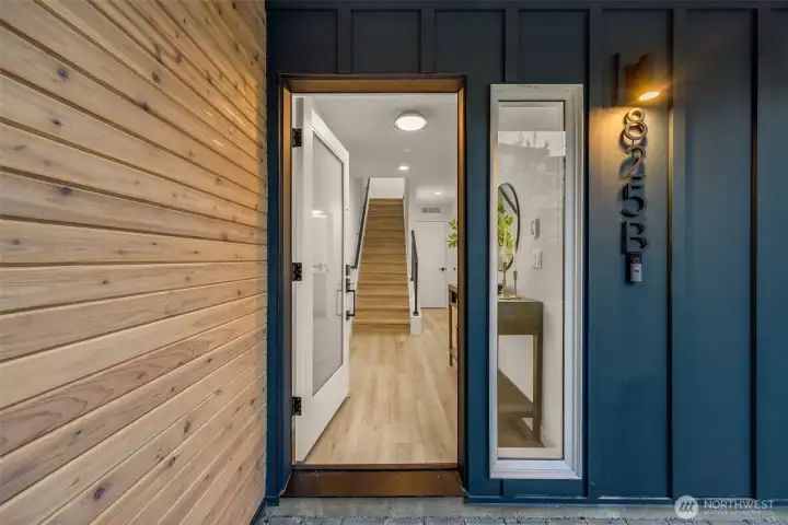 Welcoming front entry featuring warm natural wood accents and a sleek modern door (photos are of model home, similar finishes & quality)