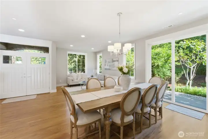 Just left of the front doors, the formal dining and living area enjoys a serene green outlook, with the patio beyond featuring fig, plum, and apple trees.