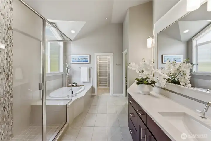 In the primary suite, the primary bathroom is bright and inviting, with a separate tub, walk-in shower, and a generous vanity. Just ahead, the California Closet walk-in closet adds exceptional floor to ceiling storage and organization