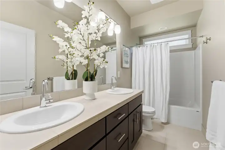 This hallway 3/4 bath serves the two additional second floor bedrooms ~ double vanity and includes attractive floor tile plus a working window for fresh air and light