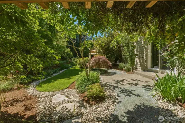 Walk beneath the wisteria arbor - a cascade of purple blossoms in early spring - and into a quiet garden oasis. Here, pink, white, and red roses create a quiet, colorful passage