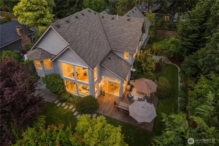 Twilight view of the home framed by lush, mature landscaping and an inviting cedar deck designed for year-round outdoor living
