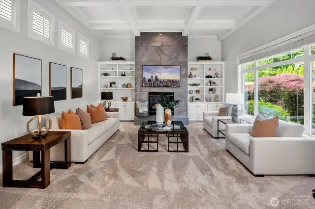 Family room with gas fireplace and large windows viewing the backyard and lush landscape.