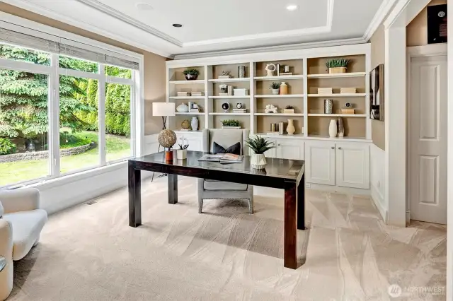 Large office area with custom built in cupboard storage space and lots of shelving.