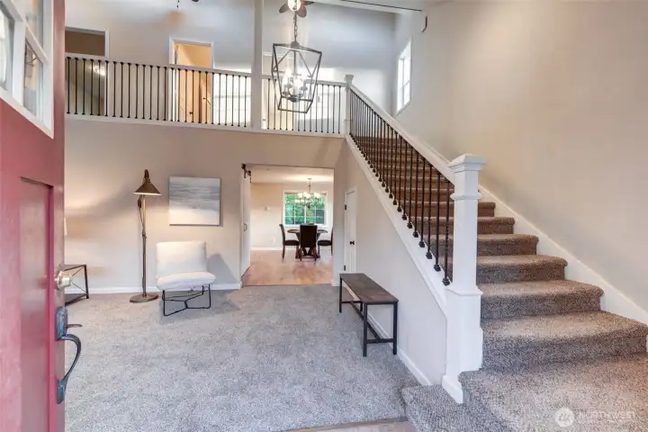 Inviting foyer opens to a bright and airy living space with high ceilings and an open starcase that sets the tone for this custom home.