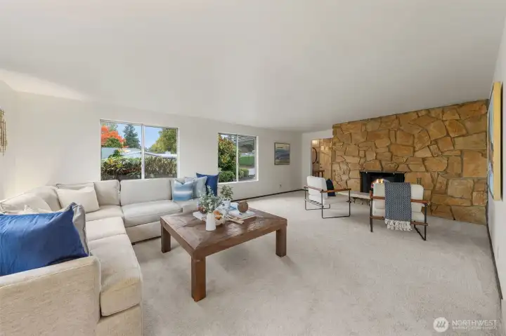 The living room is elegantly designed with a large picture window that brings in ample natural light to create a warm and inviting atmosphere. It's the ideal space for spending evenings at home in Bellevue, especially next to the charming wood fireplace.