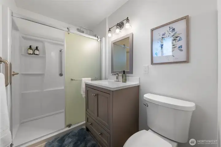 Welcome to the Primary Suite's updated bath. It features updated vanity, quartz countertop, and updated fixtures. Notice the nice shower surround that provides a great look with easy maintenance.