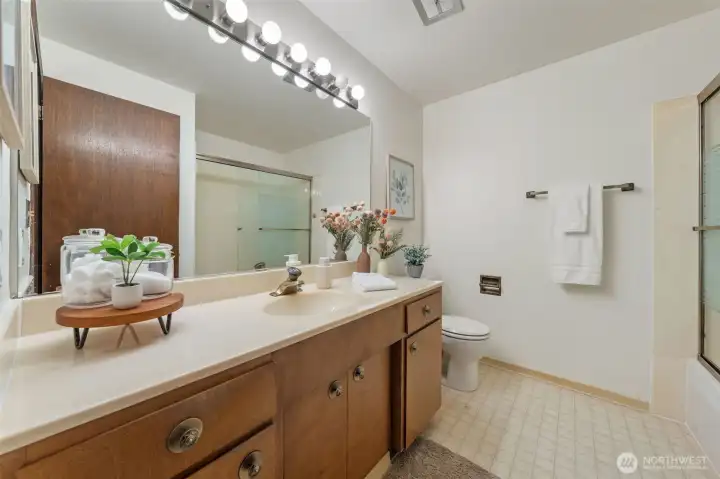 The main bath features lots of counter space, a timeless vanity, easy-care flooring, and a classic neutral tone tub/shower surround!