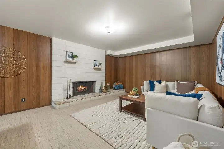 The family room features a classic wood-burning fireplace set against a block accent wall, adding warmth and character. Timeless wood paneling pairs beautifully with the neutral tones throughout the space for a welcoming and grounded atmosphere.