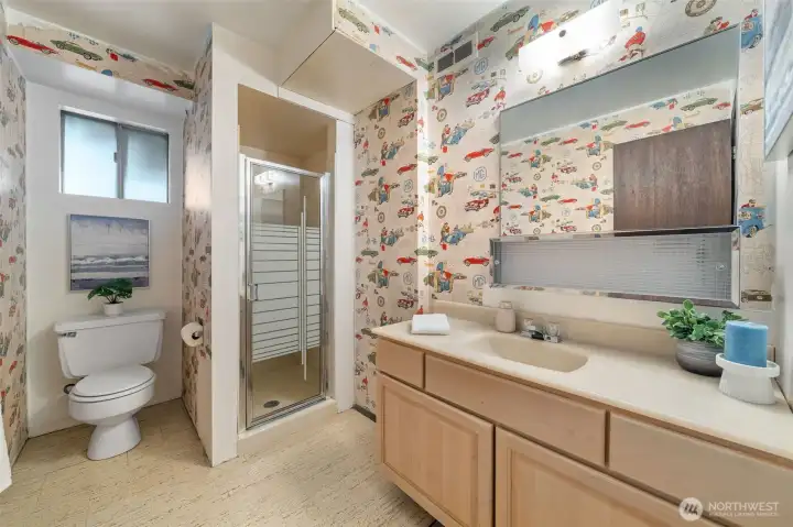The lower-level main bath includes easy-care flooring, a classic vanity, a built-in medicine cabinet, and an easy-care shower surround.