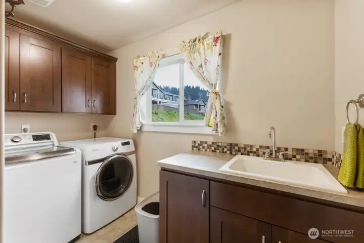 The laundry room features a utility sink and storage cabinets.