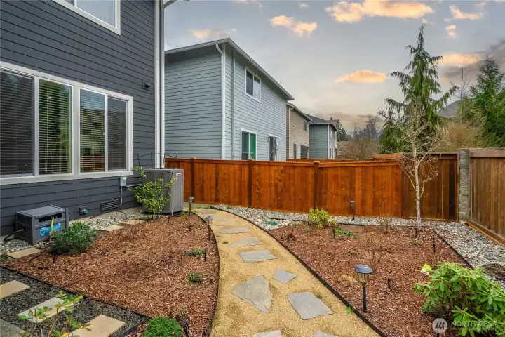 back yard has a path and so many plants waiting to bloom
