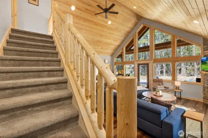 The stairway to the upper-level bunk room is accented with a rustic log railing, adding character and charm.