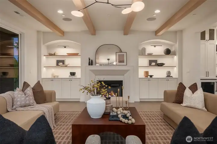 Great room with exposed beams, fireplace, and arched built-ins offering seamless flow to the kitchen and dining areas.