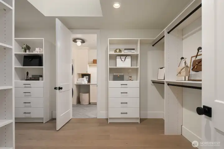 An expansive primary walk-in closet designed like a private boutique, featuring custom built-ins, generous hanging and storage, and direct access to the laundry room featuring Electrolux washer and dryers for effortless daily living.