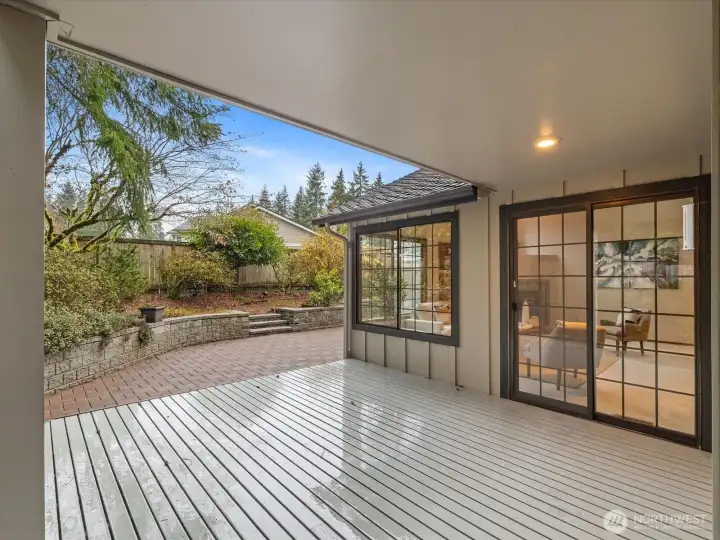 Brick paver patio with stone retaining wall and steps leading to a fully fenced area — a generously sized private outdoor space