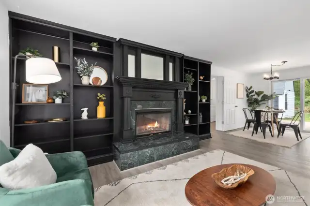 Living room with wood burning fireplace and built-in shelving opens to the dining area