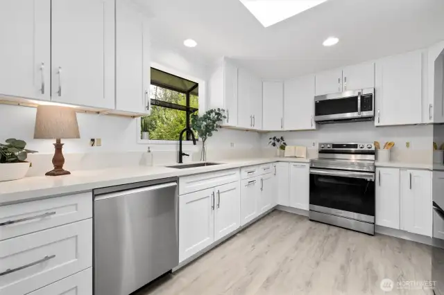 Fully remodeled kitchen with white shaker cabinets, quartz countertops, an industrial sink with matte black faucet, new skylight and all new appliances