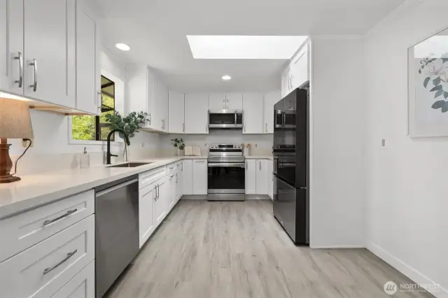 Fully remodeled kitchen with white shaker cabinets, quartz countertops, an industrial sink with matte black faucet, new skylight and all new appliances