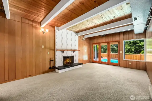 Cool downstairs living space with wood burning fireplace and french doors to outdoor pool.