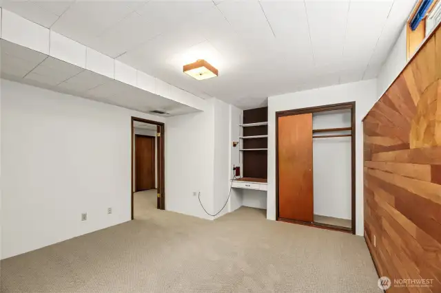 Large non-conforming bedroom downstairs with built-in desk and upper wouth facing window to right of photo. Doorway leads to laundry room, 3/4 bath on lower and shop space.