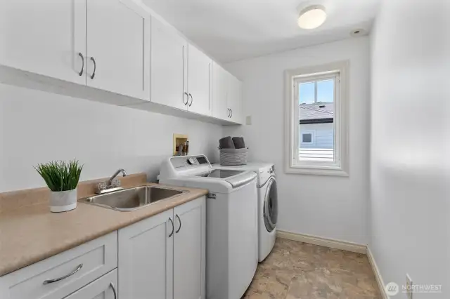 Spacious second-floor laundry room with newly updated white cabinetry, offering a bright and functional space with generous storage and work surfaces.