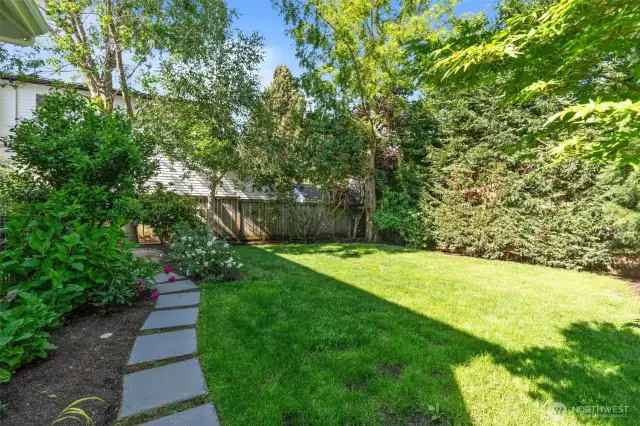 Generous outdoor space featuring a large, manicured lawn surrounded by mature landscaping, offering plenty of room for play and relaxation.