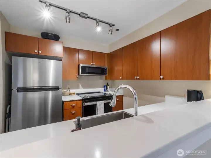 The beautifully updated kitchen with quartz surfaces, stainless steel appliances, and warm-toned LVP floors.