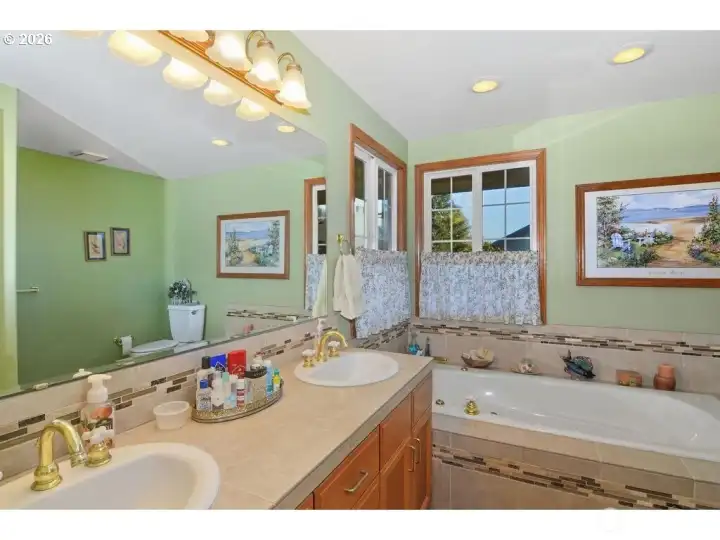 Primary bathroom features tile countertops, double sinks, a jetted tub, and a walk-in shower.