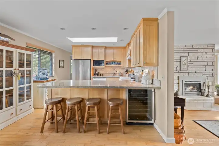 Thoughtfully redone kitchen with bar, wine fridge, custom cabinets, granite countertops, and newer SS appliances.