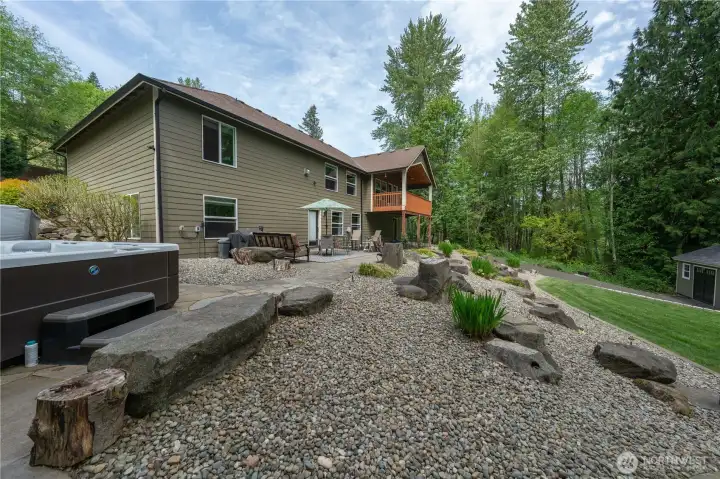 Looking past the hot tub towards the rear of the house which has three entry doors into the daylight basement which is finished with two bedrooms, a full bathroom and a rec room with potential for a MIL apartment!