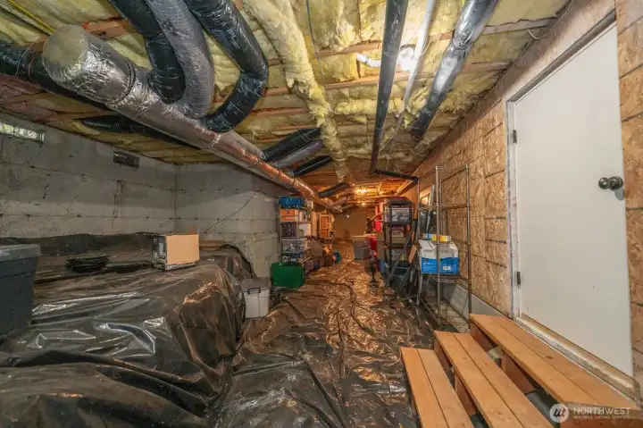 Full length of home storage space which is accessible from the ground floor bedroom.  There is an overhead light in this unfinished room.