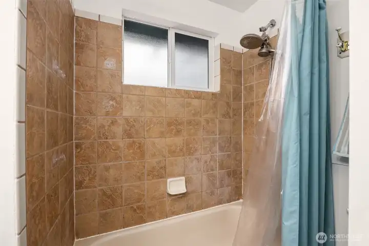 Shower & tub combo in this cozy bathroom.