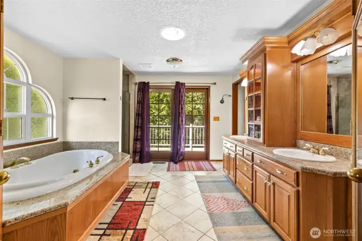 Primary piece bathroom with dual vanities and french doors leading to the deck