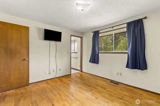 Clean slate with room to dream—this bedroom offers hardwood charm, a peek into the en suite, and built-in TV zone (cord concealer, anyone?)