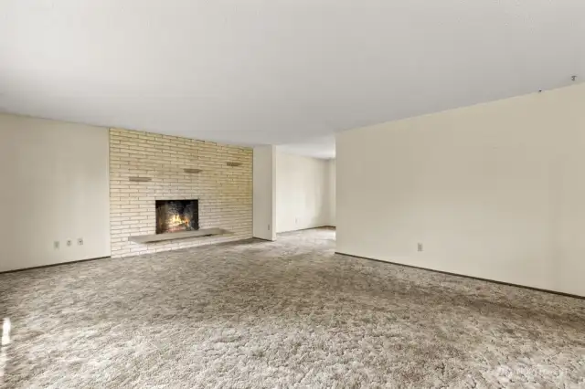 Bring the cozy! A wood-burning fireplace anchors this large upstairs living room, framed by oversized windows and plush 70s carpet that's basically begging for a glow-up.