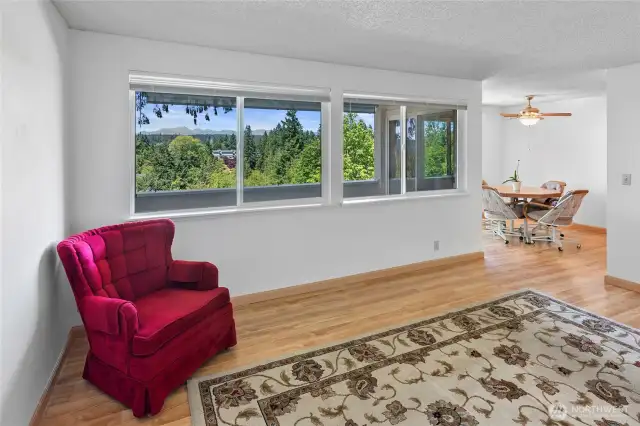 View across the living room toward the dining area. Note the large windows looking thru the deck area of the the views of the Olympic Mountain range