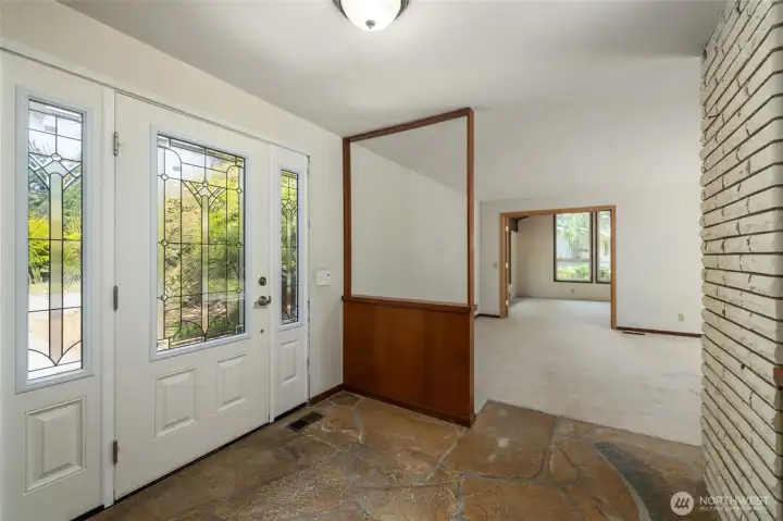 Entryway with stone floors.  Beyond the living room, French doors lead to the spacious bonus room.