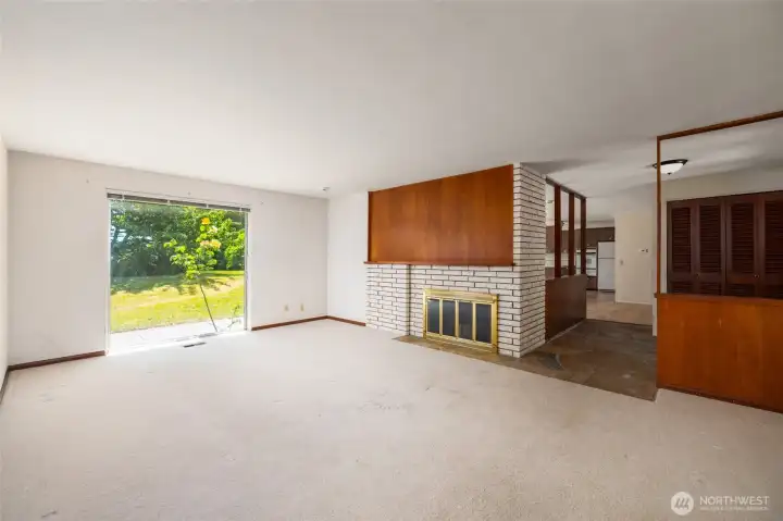 The living room, featuring another floor-to-ceiling window, is open to the entryway.  You can see the diningroom/kitchen beyond.